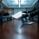 IT-professional weigert contract van directeur aan vergadertafel, laptop met beveiligingsicoon zichtbaar, gespannen sfeer.