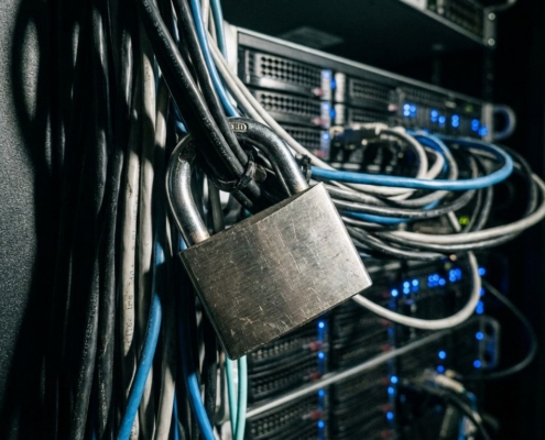 Stalen hangslot beveiligt bundel netwerkkabels in serverruimte met blauwe LED-lampjes op de achtergrond